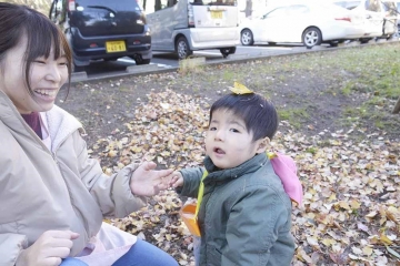 お子さんと先生が葉っぱで遊んでいる写真