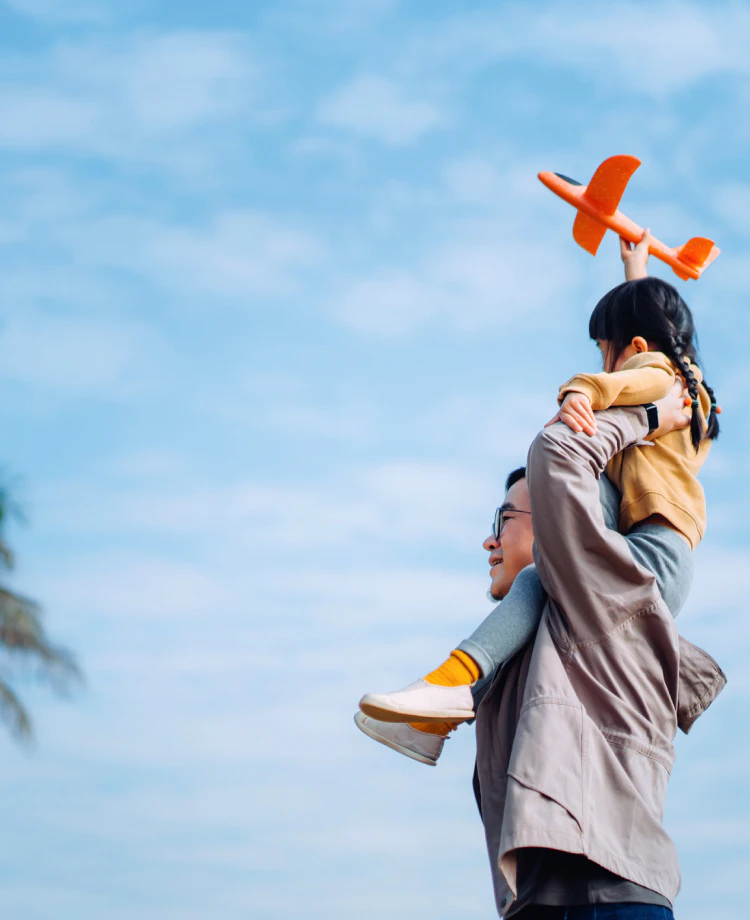 父親に肩車されてオレンジの飛行機を持つ女の子