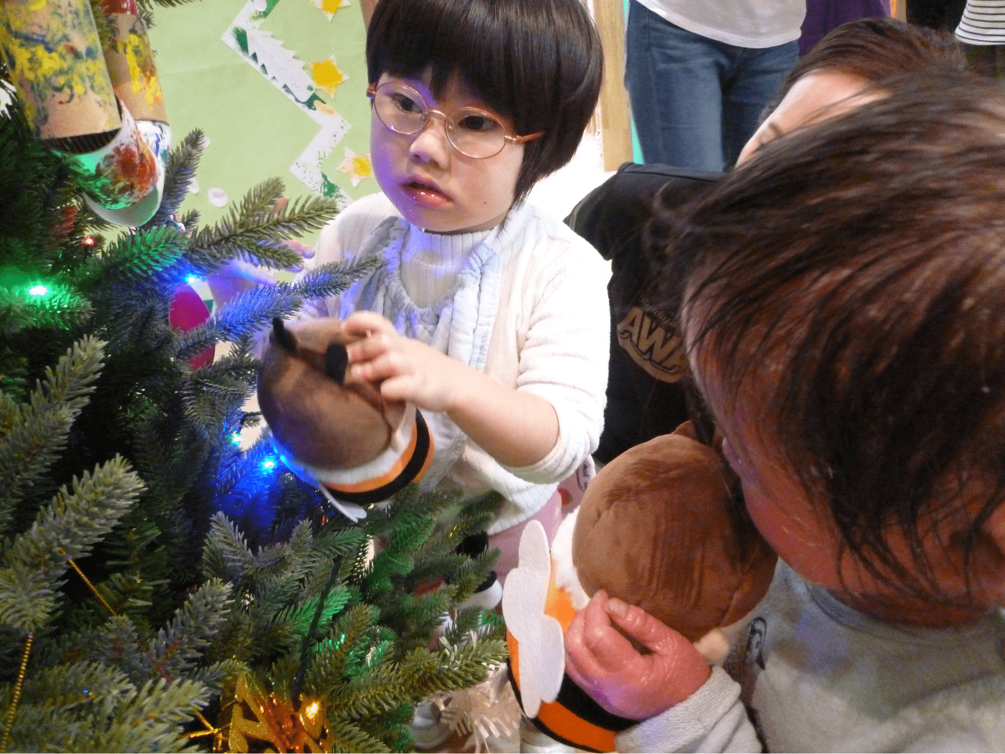 ヒカキン人形をクリスマスツリーに飾り付けする子ども達