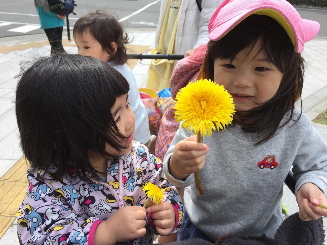 大きなたんぽぽを前に笑顔の子どもたち