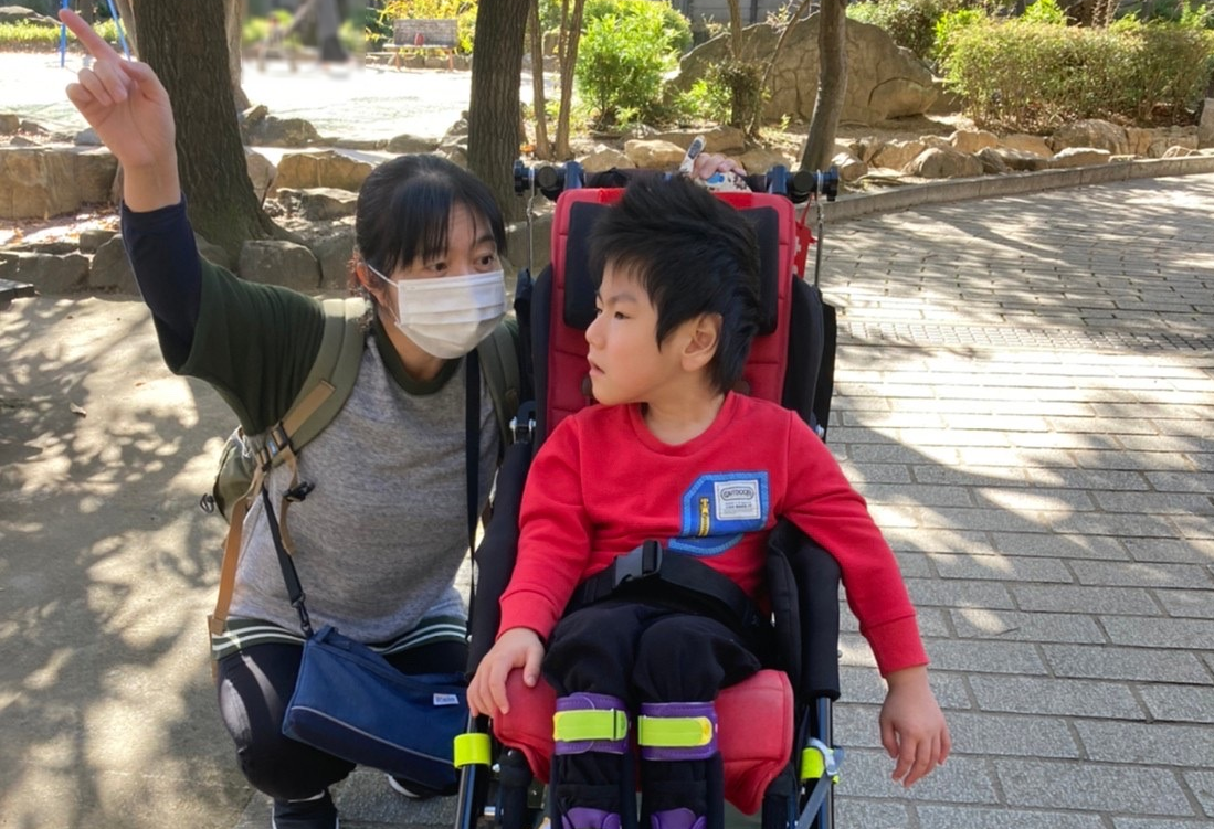 バギーに乗りながら担任の先生と公園をお散歩する医療的ケア児のお子さん。