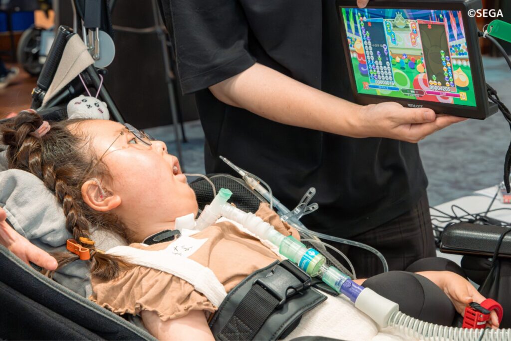 医療的なケアのあるお子さんがインクルーシブ・テックを使ってゲームを楽しんでいる様子