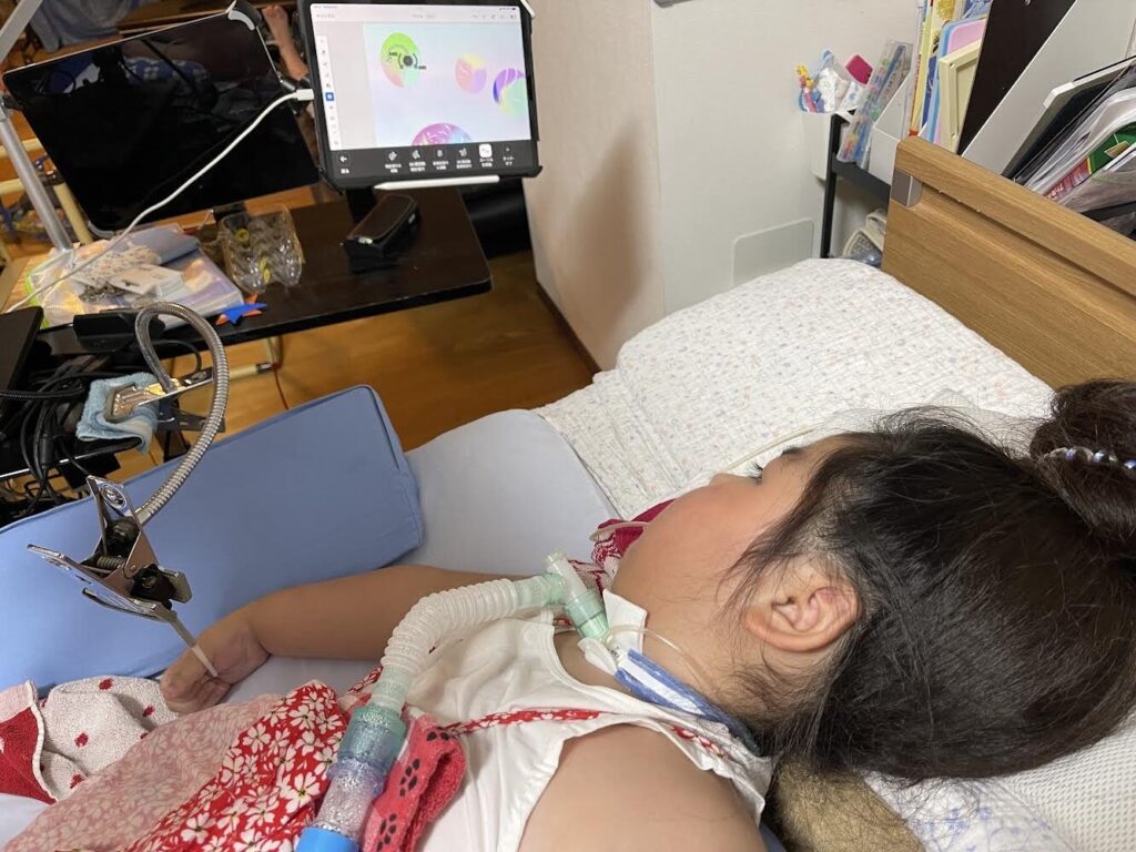 医療的なケアのあるお子さんが、指先のわずかな力で入力できるデバイスでパソコンを操作し、絵を描くことを楽しんでいる様子