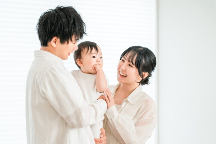 乳児を抱く幸せそうな父母のアイキャッチ画像