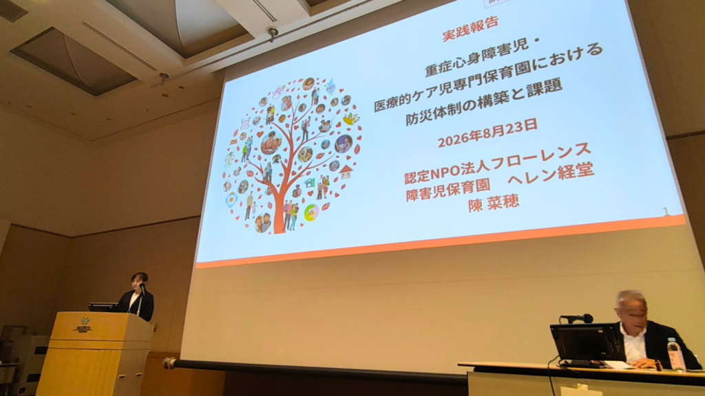 学会で、壇上に陳園長が立ちスライド発表をしている様子。